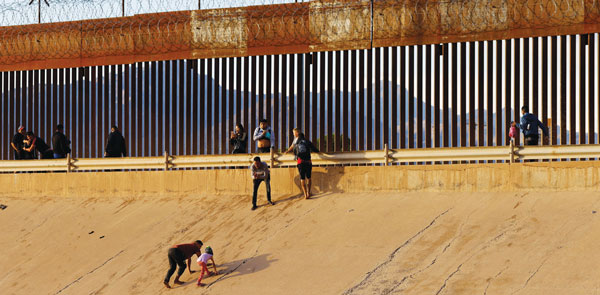 미·멕시코 국경 장벽 넘는 난민 신청 이민자들
